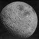 The moon's pockmarked far face looms in the darkness of space.